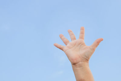 Low angle view of human hand against clear sky