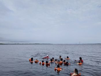 People swimming in sea against sky