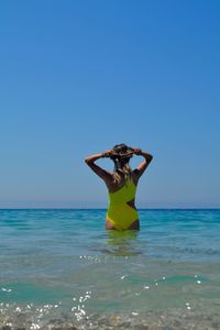 Rear view of woman standing in sea against clear sky