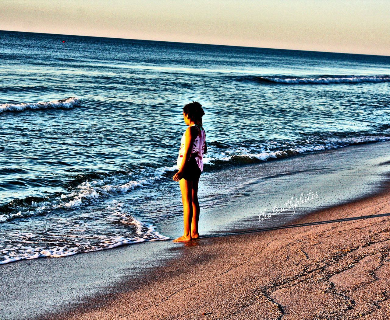 WOMAN STANDING ON BEACH AGAINST SEA