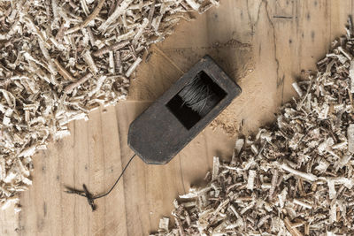 High angle view of work tool amidst shavings on wooden table