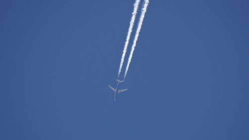 Low angle view of airplane flying against blue sky