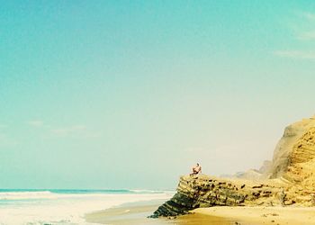 Woman standing on beach against clear blue sky