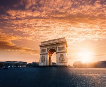 Triumphal arch against sky at sunset