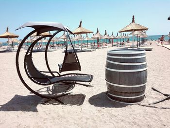 Chairs on beach by sea against sky