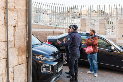 People standing by car on road