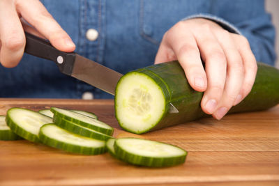 Midsection of person cutting cucumber