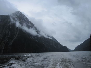Scenic view of sea by mountains against sky