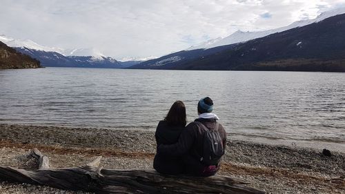 Rear view of people looking at lake against mountains