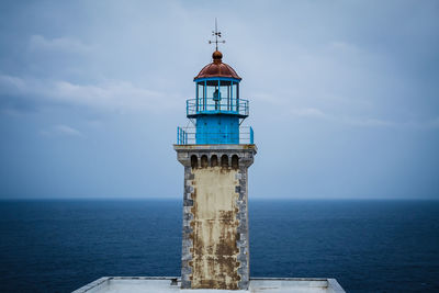 Lighthouse by sea against sky