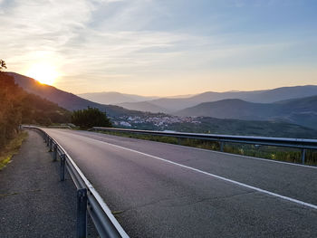 Road by mountains against sky during sunset