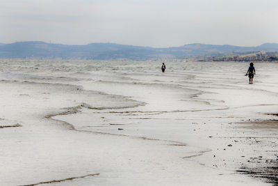 People walking on beach against sky