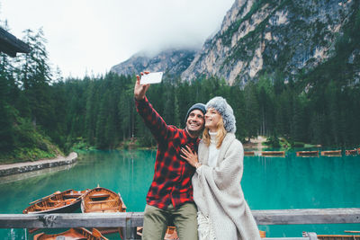 Young woman photographing while standing by lake