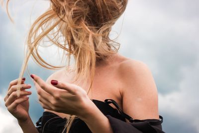 Young woman with blond tousled hair against sky