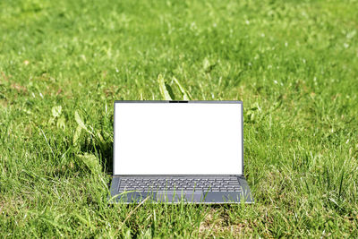 Close-up of laptop on grassy field