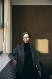 Portrait of young woman standing against wall