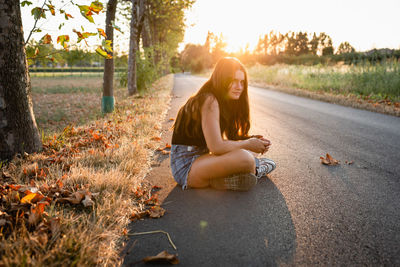 Portrait of young woman sitting on road