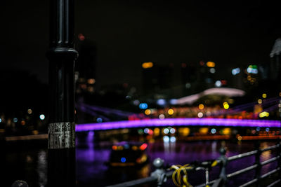 Illuminated bridge over river in city at night