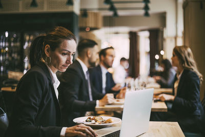 Side view of businesswoman using laptop in restaurant