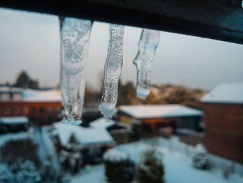 Close-up of icicles against built structure in winter