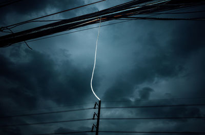 Low angle view of electricity pylon against storm clouds