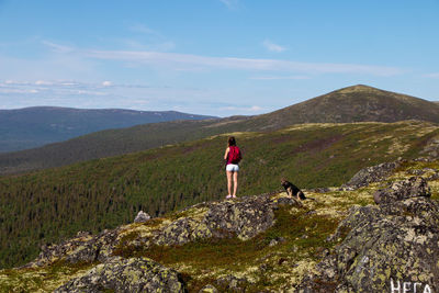 Rear view of people standing on mountain against sky