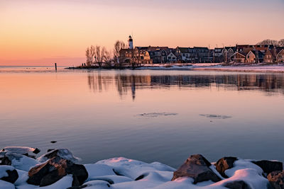 Reflection of buildings in sea during sunset