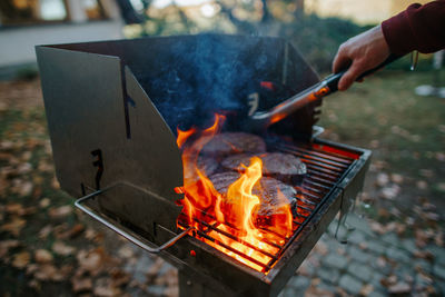 Cropped image of man preparing food on barbecue grill in yard