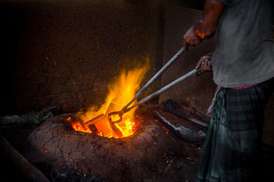 Low angle view of man working on fire at night