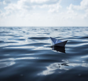 Close-up of paper floating on sea against sky