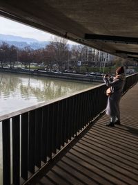 Rear view of people standing on bridge over water