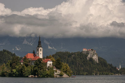 Lighthouse amidst buildings and sea against sky