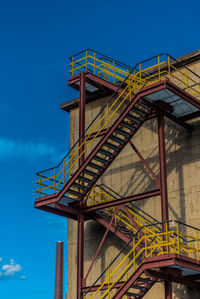 Low angle view of bridge against buildings against blue sky