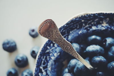 Close-up of patterned spoon on blueberries in bowl at table