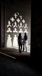 Rear view of couple walking against wall