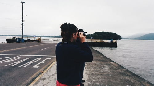 Rear view of man photographing sea against sky