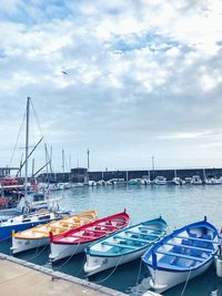 Boats moored at harbor against sky