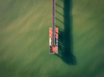 Fishermen on a pier in the middle of green sea water at sunrise with long shadows