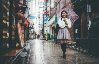 Full length of young woman standing on road in city