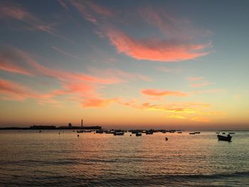 Boats in calm sea at sunset