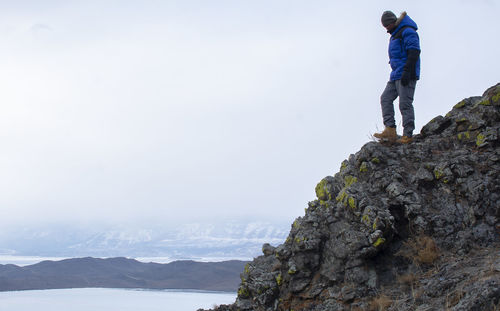 Man standing on rock against sky