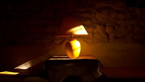 Low angle view of illuminated light bulb against wall in the dark