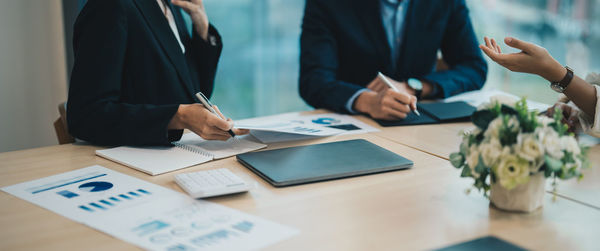 Midsection of business colleagues working on table