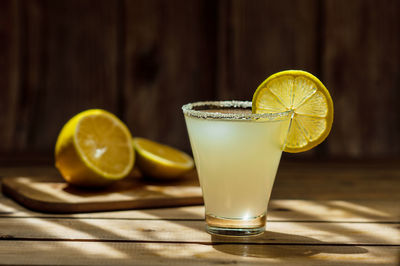 Summer alcoholic yellow frosted drink in a transparent shaped glass with sugar on the rim 