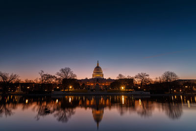 Illuminated united states capital dome with reflection on river at dusk