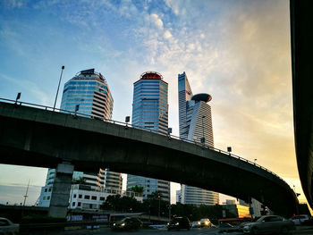 Low angle view of skyscrapers against cloudy sky