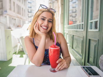 Portrait of a smiling young woman sitting on table