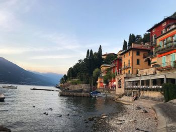 Houses by sea in town against sky