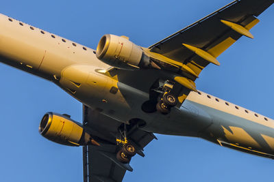 Low angle view of airplane flying against clear blue sky