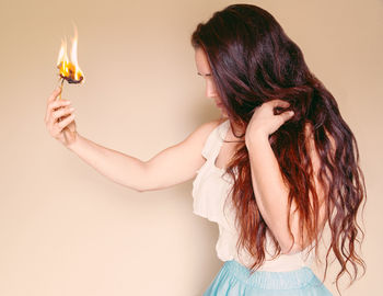 Long haired woman sadly holding burning flower